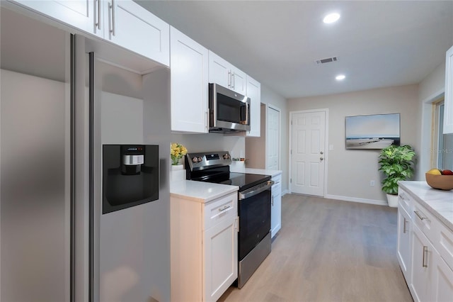 kitchen featuring appliances with stainless steel finishes, light hardwood / wood-style flooring, and white cabinetry