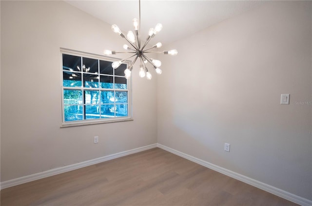 spare room featuring wood-type flooring and an inviting chandelier