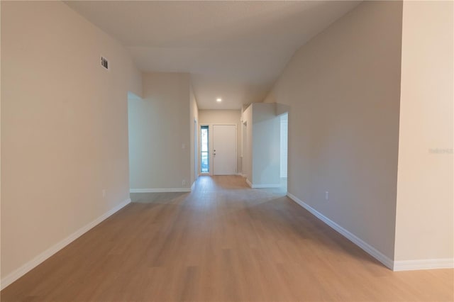 corridor with light wood-type flooring and vaulted ceiling