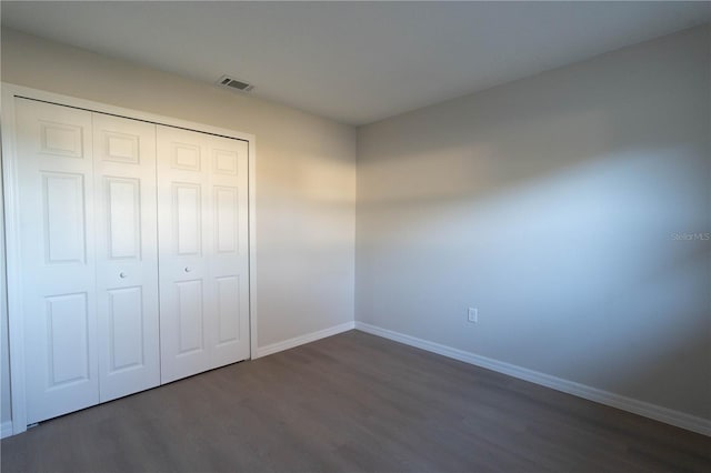 unfurnished bedroom with dark hardwood / wood-style flooring and a closet