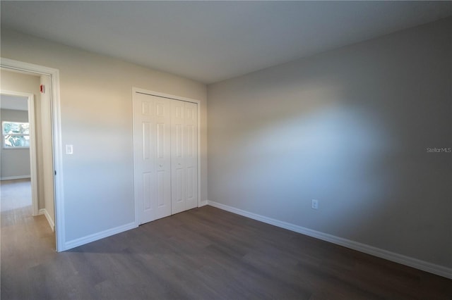 unfurnished bedroom with a closet and dark hardwood / wood-style floors