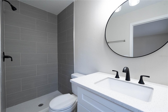 bathroom featuring vanity, toilet, and a tile shower