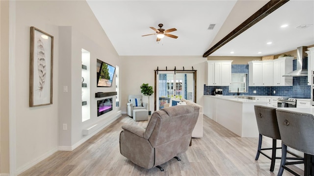 living room with vaulted ceiling with beams, ceiling fan, and light wood-type flooring