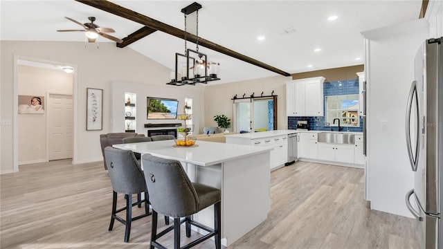 kitchen with white cabinetry, hanging light fixtures, stainless steel appliances, tasteful backsplash, and a breakfast bar