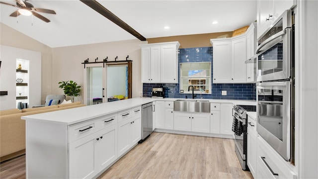 kitchen featuring kitchen peninsula, appliances with stainless steel finishes, backsplash, sink, and white cabinets