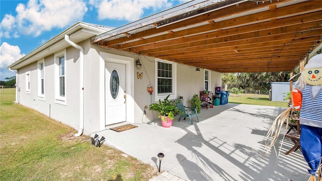 doorway to property with a yard and a patio