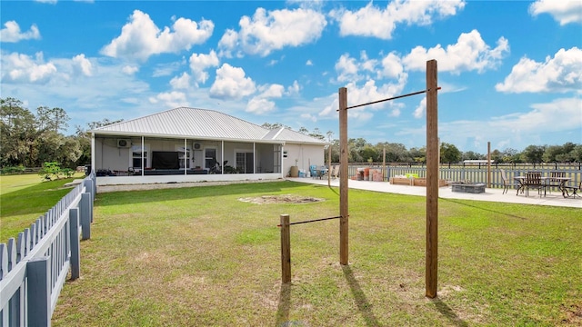 rear view of property featuring an outdoor fire pit, a lawn, a patio area, and a sunroom