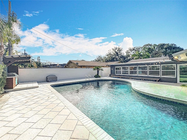 view of swimming pool with a sunroom, a patio, fence, and a fenced in pool