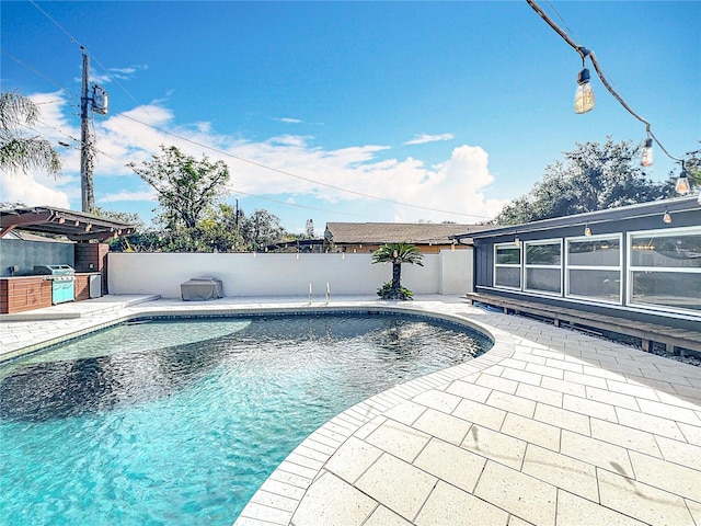 view of swimming pool with a fenced backyard, a fenced in pool, exterior kitchen, and a patio