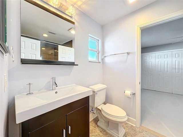 bathroom with visible vents, toilet, vanity, baseboards, and walk in shower