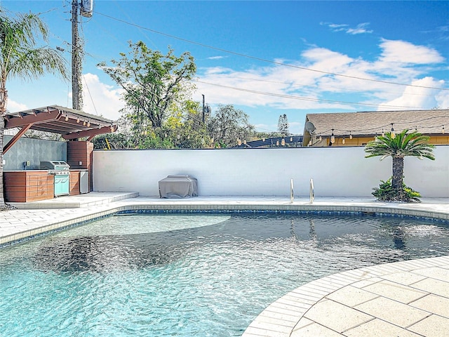 view of swimming pool with exterior kitchen, a patio area, a fenced in pool, and a fenced backyard