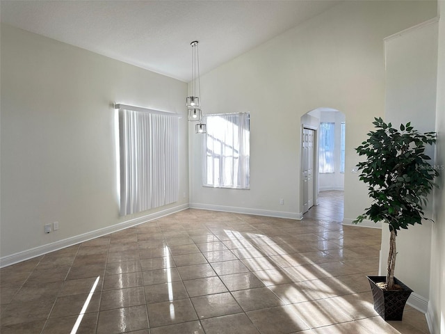 unfurnished dining area featuring tile patterned floors and high vaulted ceiling