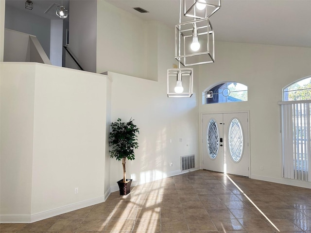 entrance foyer featuring french doors, a towering ceiling, and dark tile patterned floors