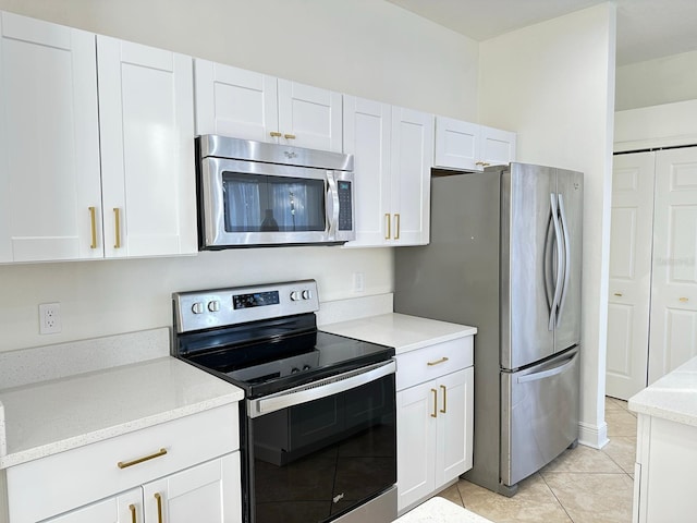 kitchen featuring light stone countertops, white cabinets, light tile patterned floors, and appliances with stainless steel finishes