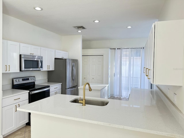 kitchen featuring white cabinetry, sink, stainless steel appliances, light stone counters, and light tile patterned floors