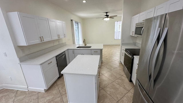 kitchen featuring kitchen peninsula, stainless steel appliances, sink, white cabinetry, and a kitchen island