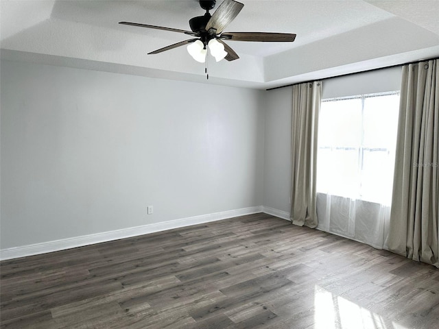 unfurnished room with a tray ceiling, ceiling fan, wood-type flooring, and a textured ceiling