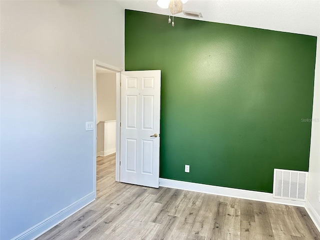 spare room with ceiling fan, light hardwood / wood-style floors, and a high ceiling