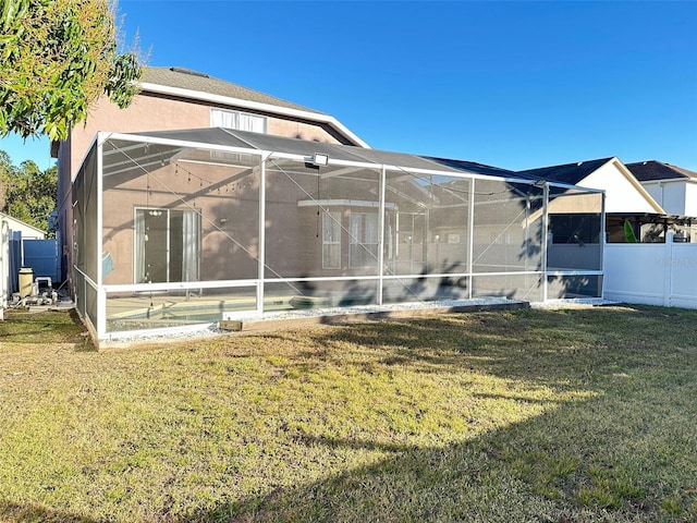 rear view of house with a lanai and a lawn