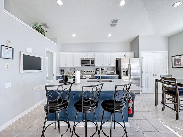 kitchen featuring white cabinets, a center island with sink, sink, and appliances with stainless steel finishes