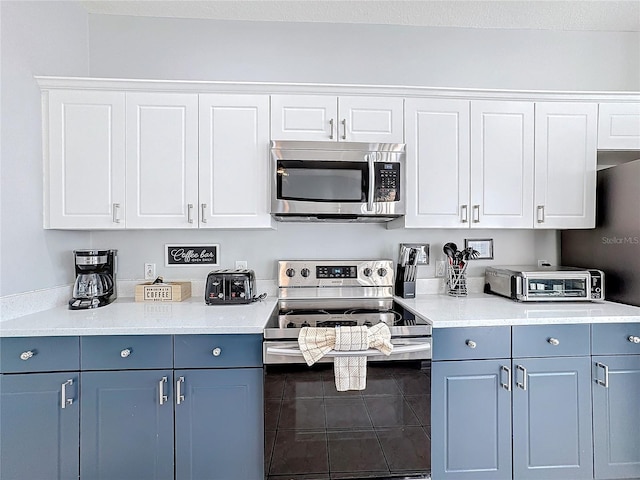 kitchen with white cabinets, blue cabinetry, and appliances with stainless steel finishes