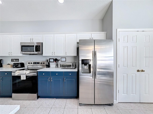 kitchen with blue cabinetry, stainless steel appliances, white cabinetry, and light tile patterned flooring