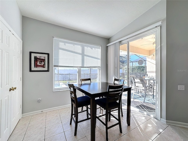 dining area with light tile patterned floors, a textured ceiling, and vaulted ceiling