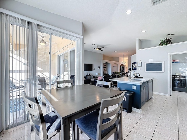 tiled dining space with a textured ceiling, ceiling fan, washer / dryer, and sink