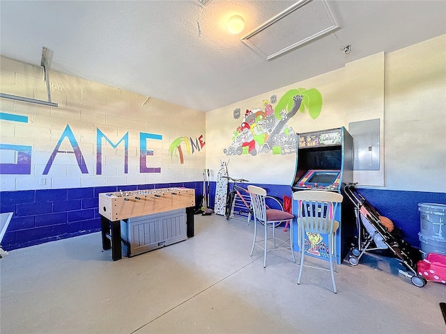 rec room with electric panel, concrete floors, and a textured ceiling