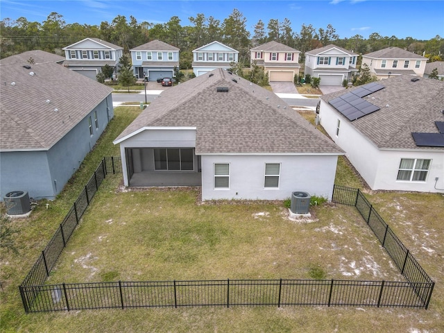 rear view of property with solar panels, central AC, a sunroom, and a lawn