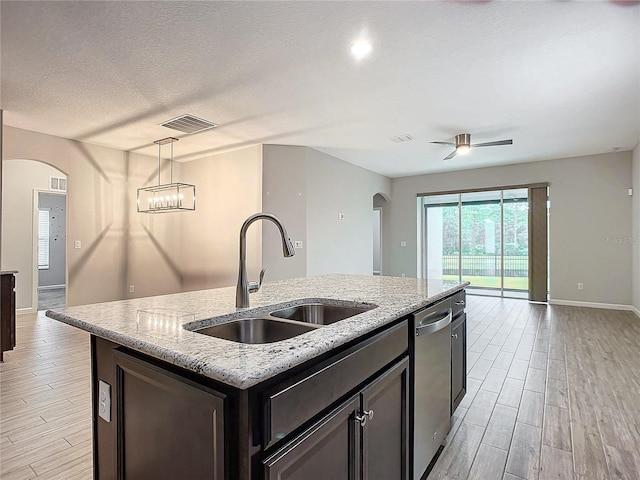 kitchen featuring sink, dishwasher, pendant lighting, light stone countertops, and a kitchen island with sink