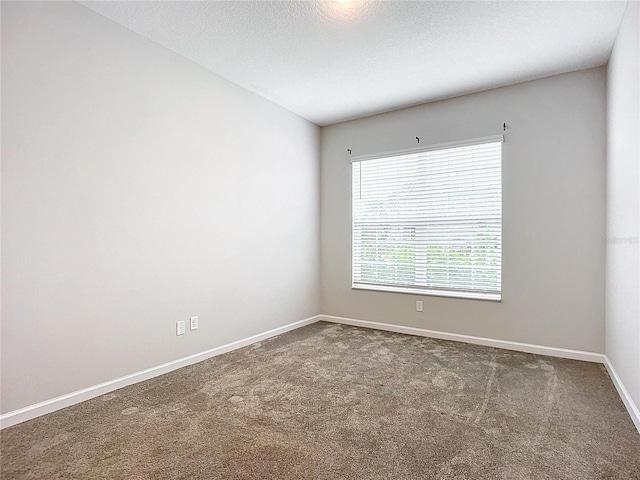 spare room with a textured ceiling and dark colored carpet