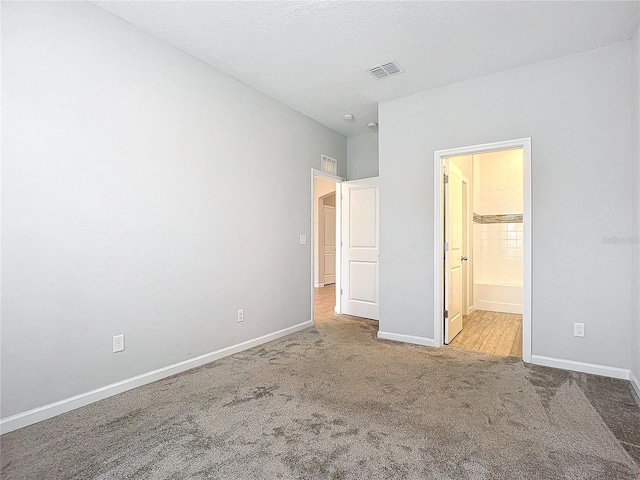 unfurnished bedroom featuring ensuite bath and light carpet