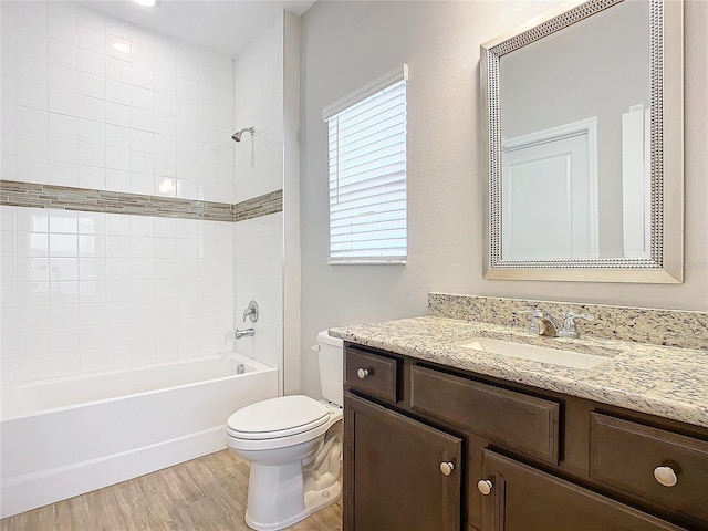 full bathroom featuring toilet, tiled shower / bath combo, vanity, and hardwood / wood-style floors