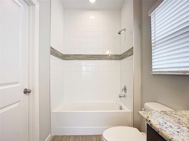 full bathroom featuring tiled shower / bath, toilet, vanity, and wood-type flooring