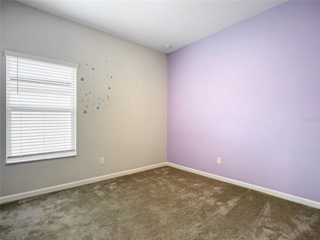 unfurnished room with dark colored carpet and plenty of natural light