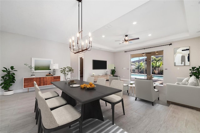 dining space featuring ceiling fan with notable chandelier and a tray ceiling