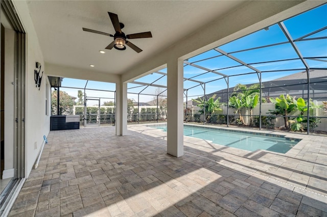 view of swimming pool with glass enclosure, ceiling fan, and a patio