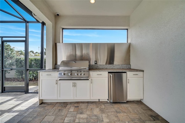 kitchen featuring light stone countertops, fridge, and white cabinets