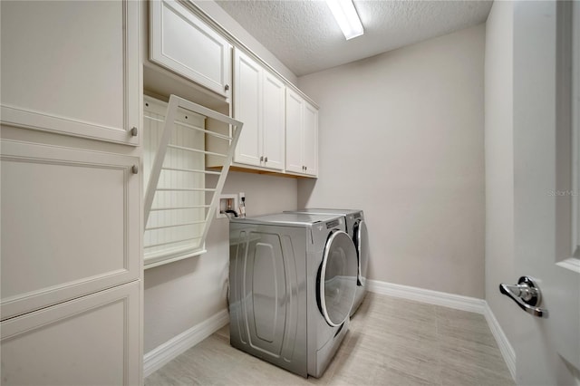 clothes washing area featuring cabinets, separate washer and dryer, and a textured ceiling