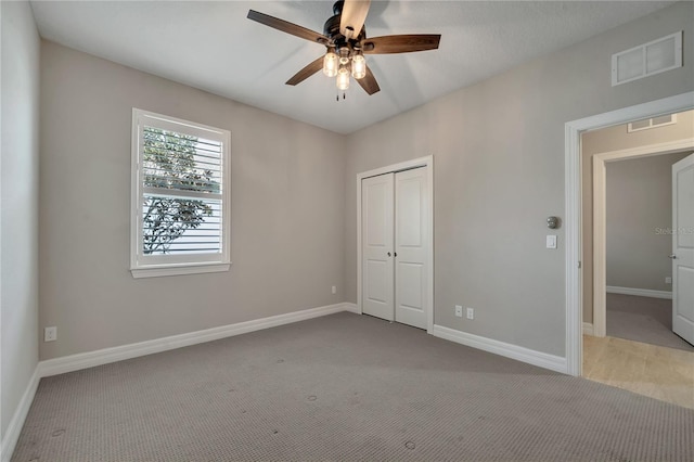 unfurnished bedroom with ceiling fan, light colored carpet, and a closet