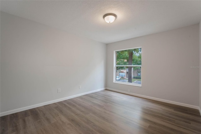 empty room featuring a textured ceiling and dark hardwood / wood-style floors