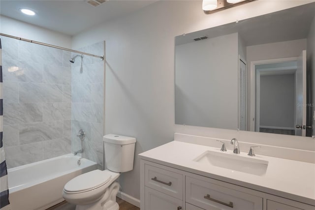 full bathroom featuring vanity, tiled shower / bath combo, and toilet