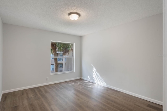 empty room with hardwood / wood-style floors and a textured ceiling