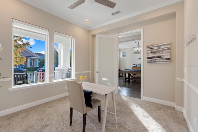 dining area with a wealth of natural light, carpet floors, ceiling fan with notable chandelier, and ornamental molding