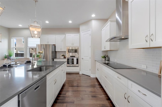 kitchen with wall chimney exhaust hood, stainless steel appliances, sink, pendant lighting, and white cabinets