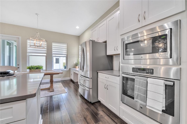 kitchen featuring white cabinets, dark hardwood / wood-style floors, pendant lighting, and appliances with stainless steel finishes