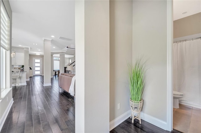 hallway featuring dark hardwood / wood-style floors and ornate columns