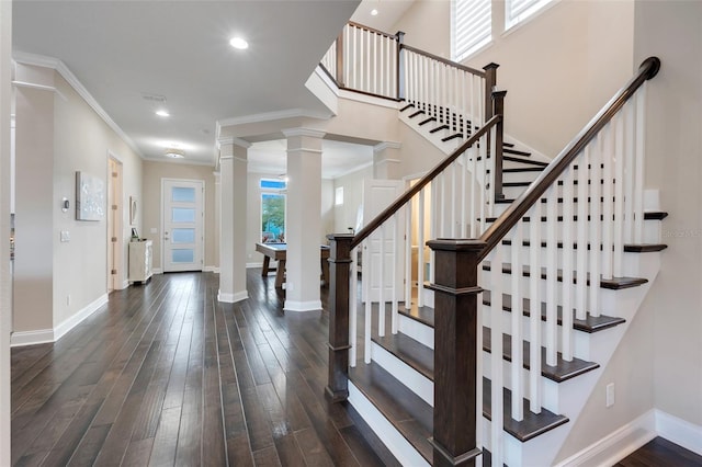 entryway featuring a healthy amount of sunlight, crown molding, ornate columns, and dark wood-type flooring