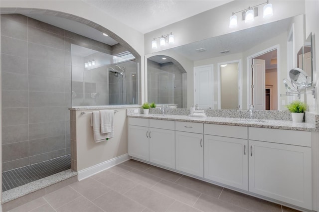 bathroom featuring tiled shower, a textured ceiling, vanity, and tile patterned flooring